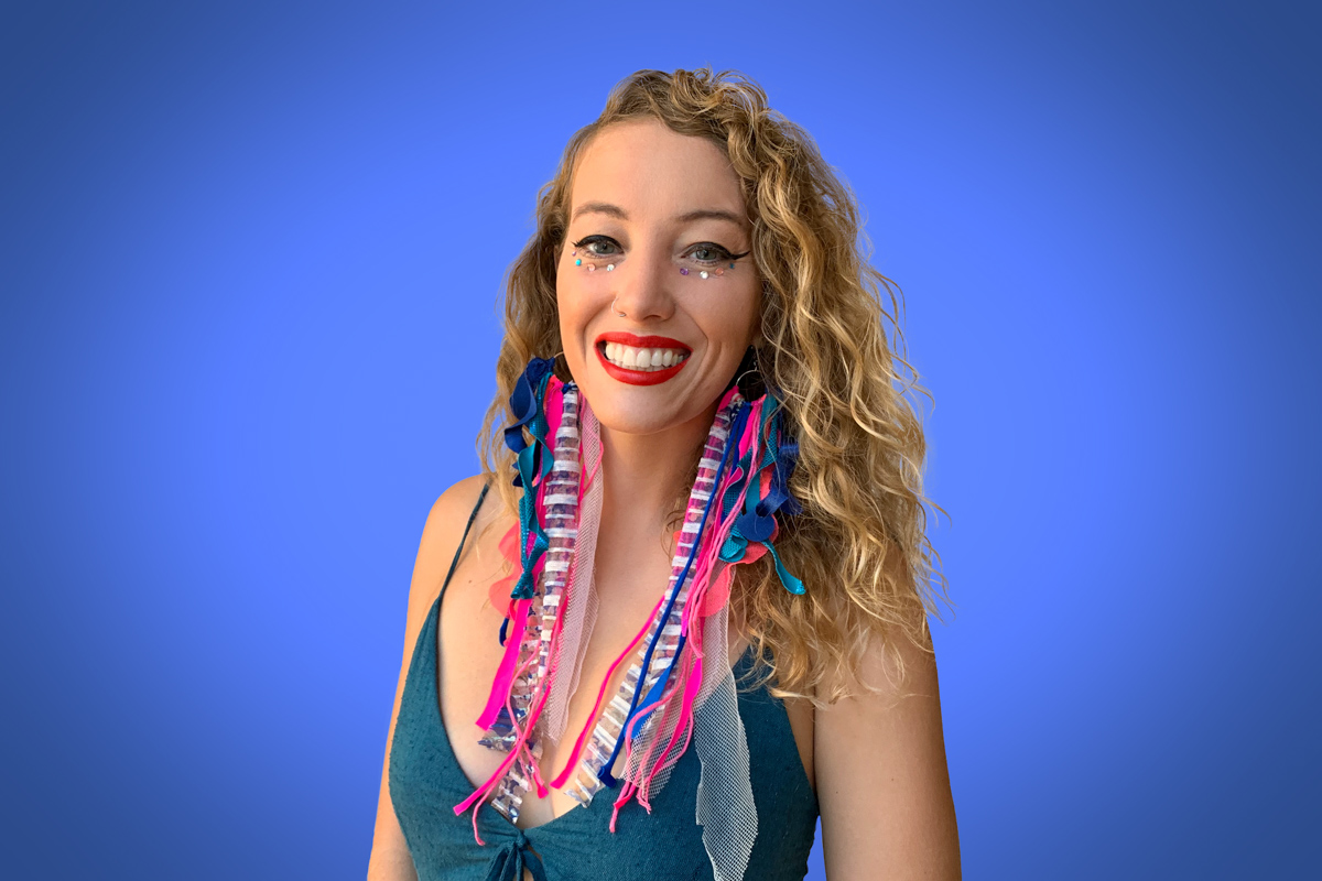 Heroic Headshot on blue background of woman in colorful clothes taking remote virtual headshot.