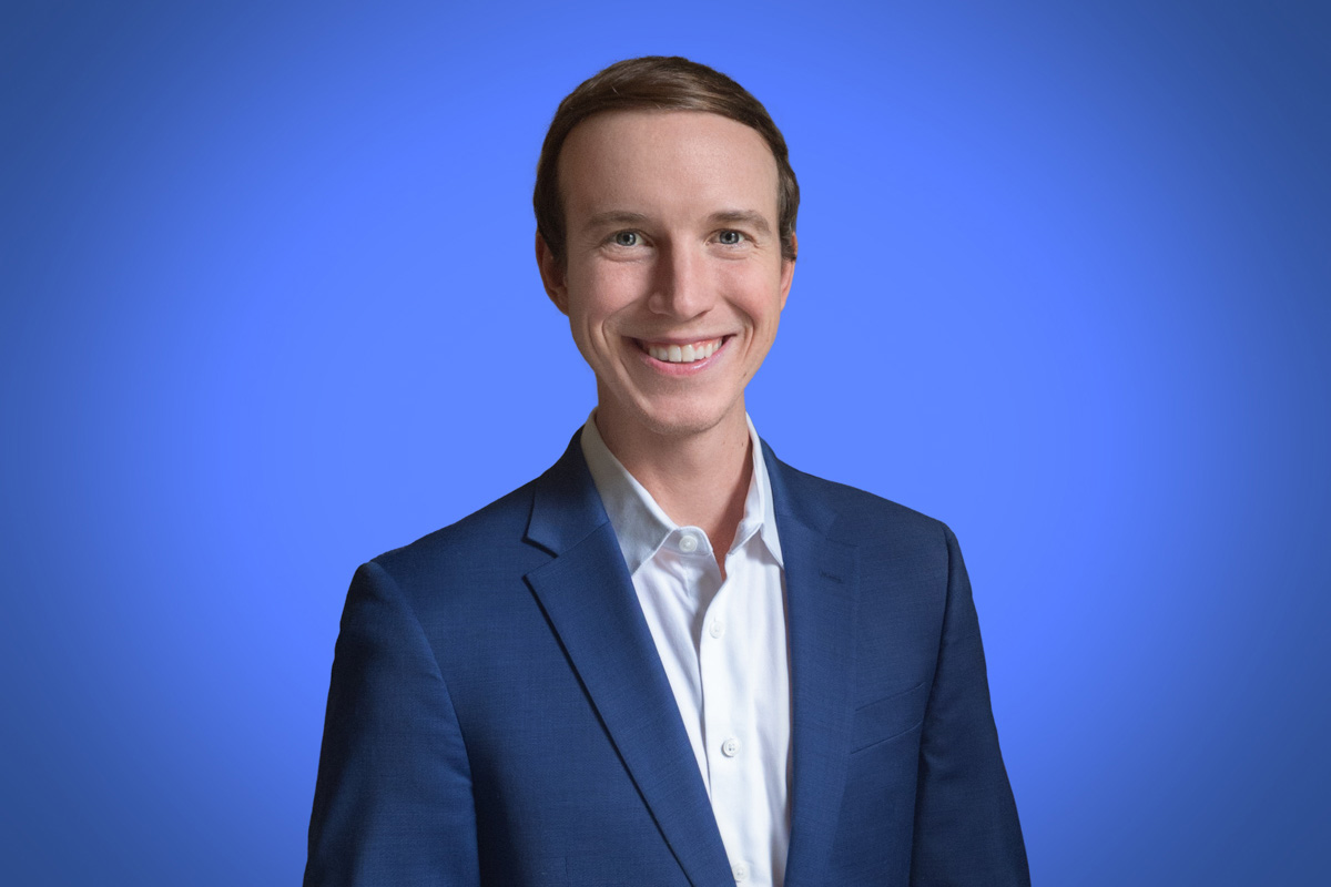 Heroic Headshot on blue background of business man in suit taking remote virtual headshot