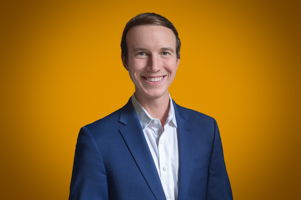 Heroic Headshot on orange background of business man in suit taking remote virtual headshot