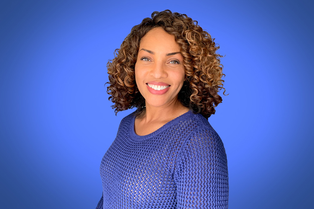 Heroic Headshot on blue background of business casual woman taking remote virtual headshot.