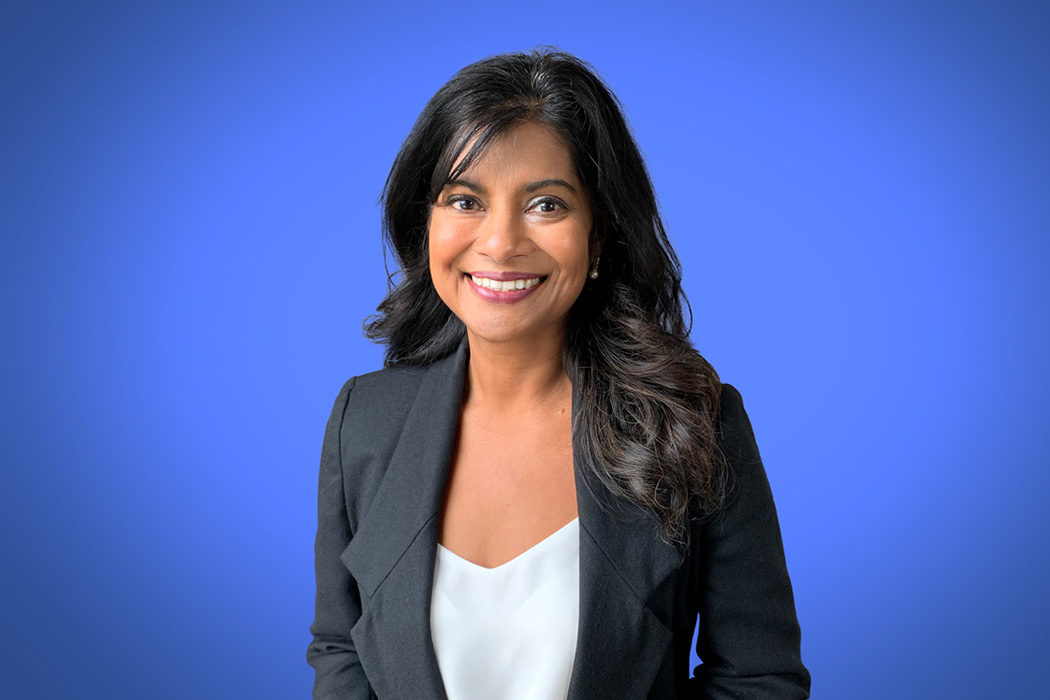 Heroic Headshot on blue background of business woman in suit jacket taking remote virtual headshot.