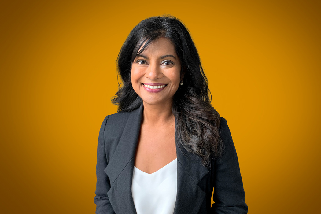 Heroic Headshot on orange background of business woman in suit jacket taking remote virtual headshot.